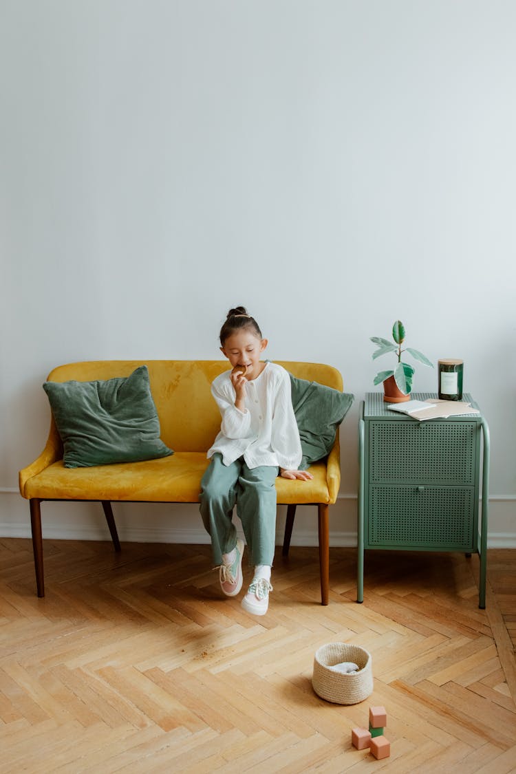 Girl Eating Cookie On Sofa With Her Eyes Closed