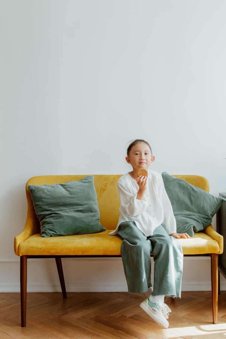 Girl Eating Cookie Sitting On Sofa