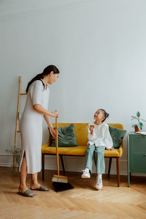 Mother Sweeping and Daughter Eating Cookie