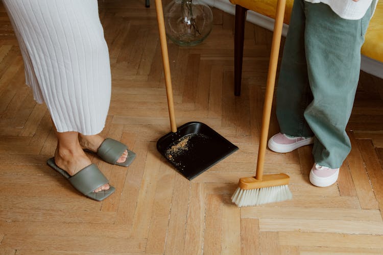 Legs Of Mother And Daughter Sweeping Floor