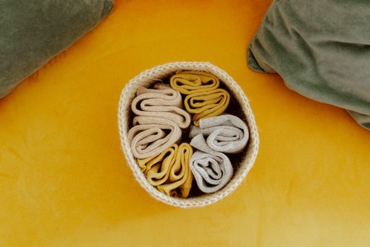 Top-down view of neatly arranged woolen socks in a basket on a vibrant yellow surface.