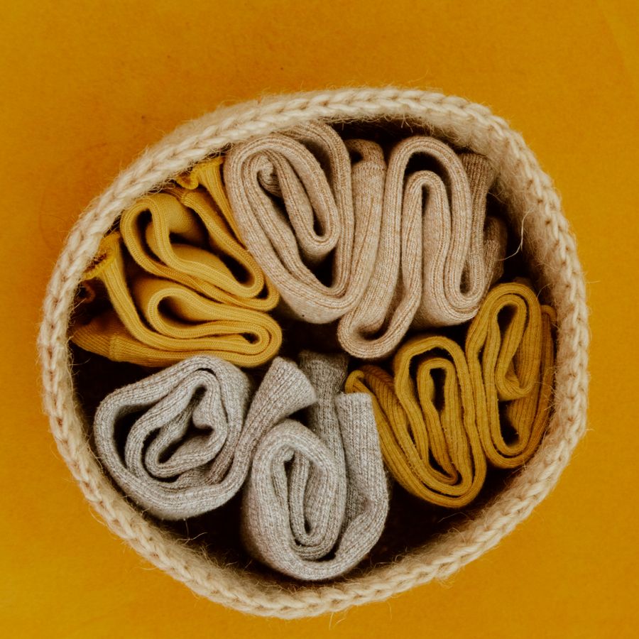 Rolled ochre and oat crew socks in a woven basket — photo by Ron Lach on Pexels