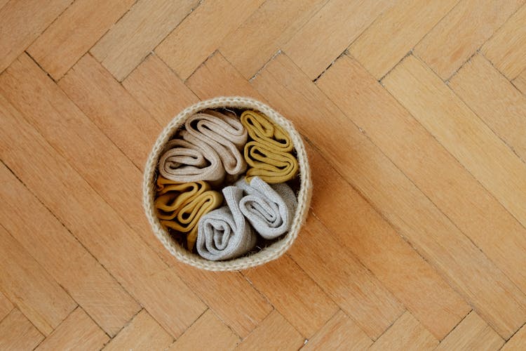 Directly Above View Of Socks In Knitted Container On Wooden Floor