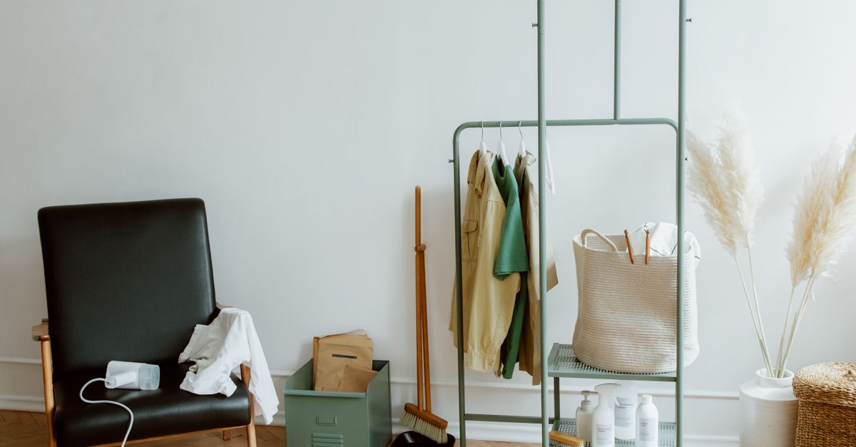 Um canto aconchegante e minimalista de casa com uma cadeira de couro preta e um cabideiro.