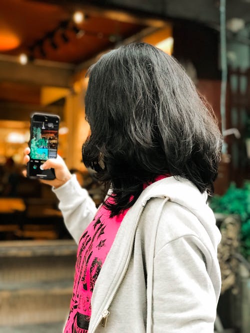 Woman Wearing a Jacket Holding a Smartphone