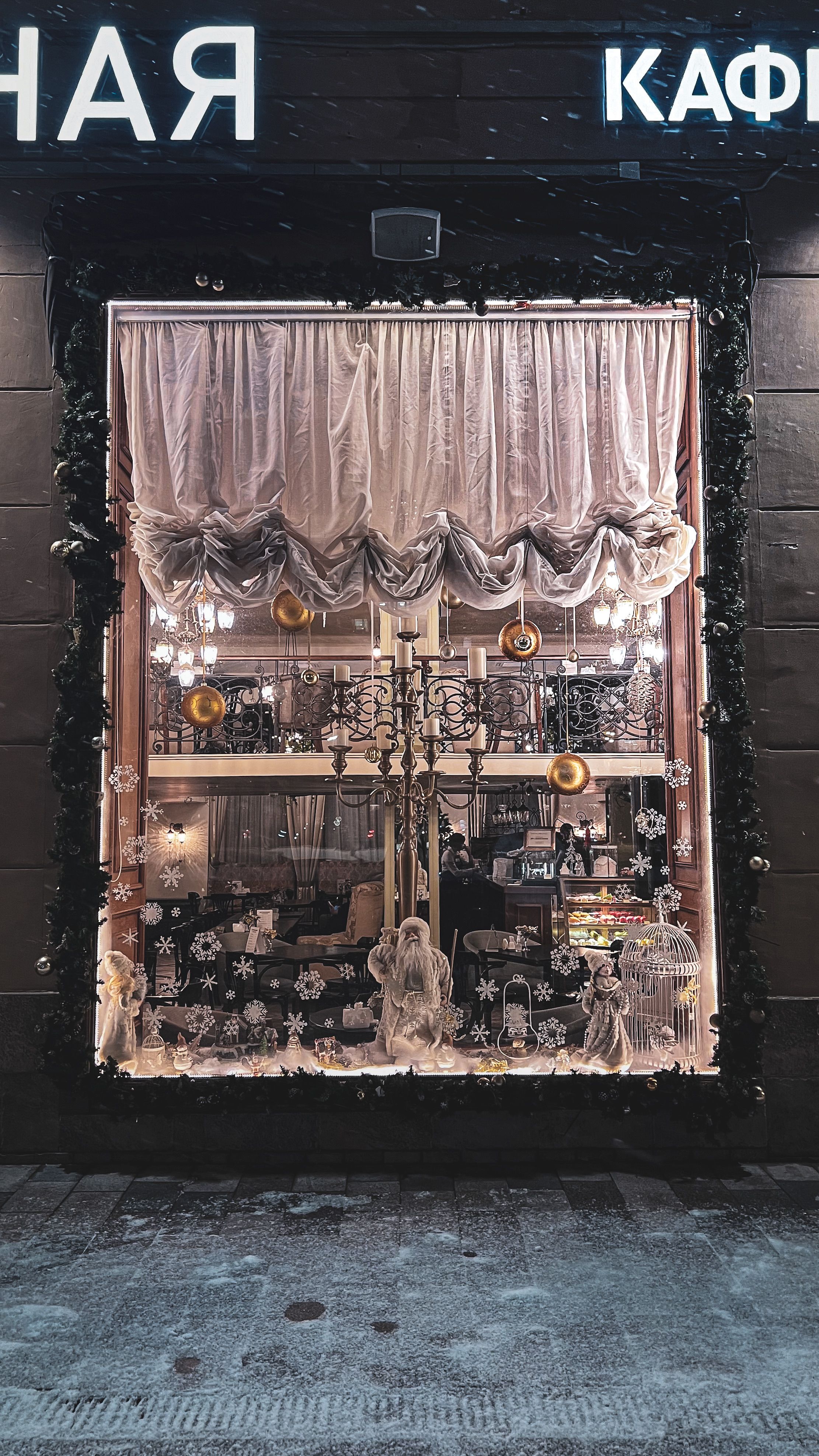 Charming Christmas-themed window display with snowy decorations and soft lighting, ideal for festive shopping inspirations.