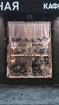 Charming Christmas-themed window display with snowy decorations and soft lighting, ideal for festive shopping inspirations.