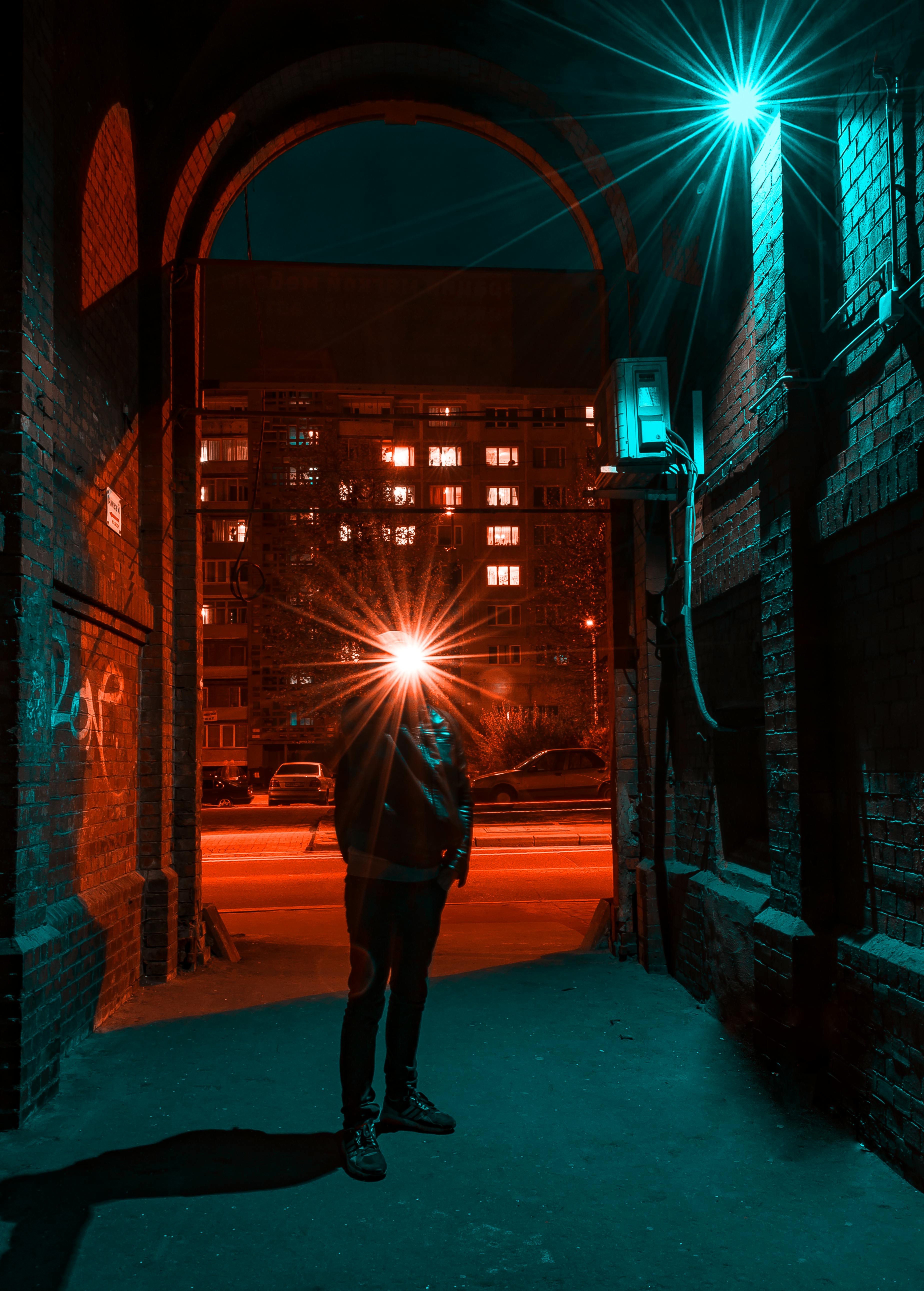 夜晚，一个孤独的人影站在灯火通明、充满活力的城市小巷中，构成了戏剧性的城市景观