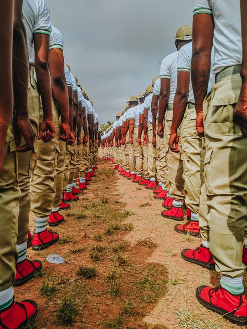 Free Soldiers in uniform stand in perfect alignment during a military parade in a grassy field. Stock Photo
