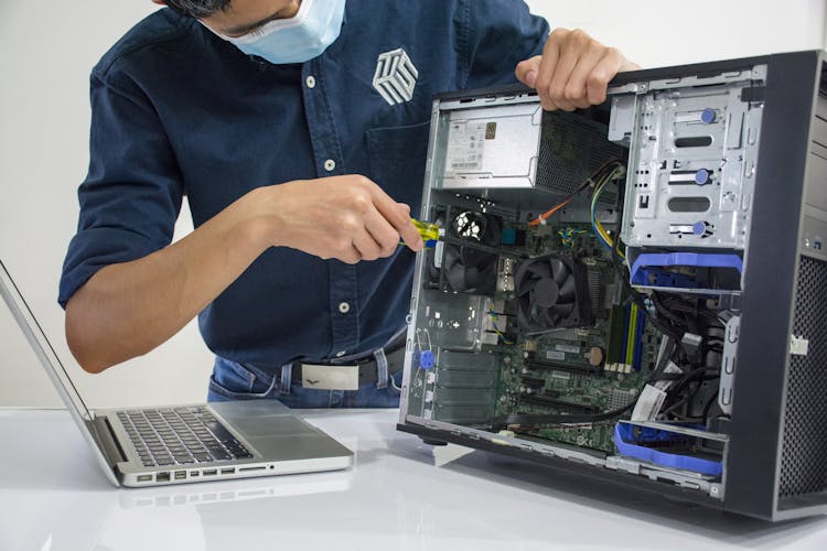 A Man Wearing A Face Mask Repairing A CPU