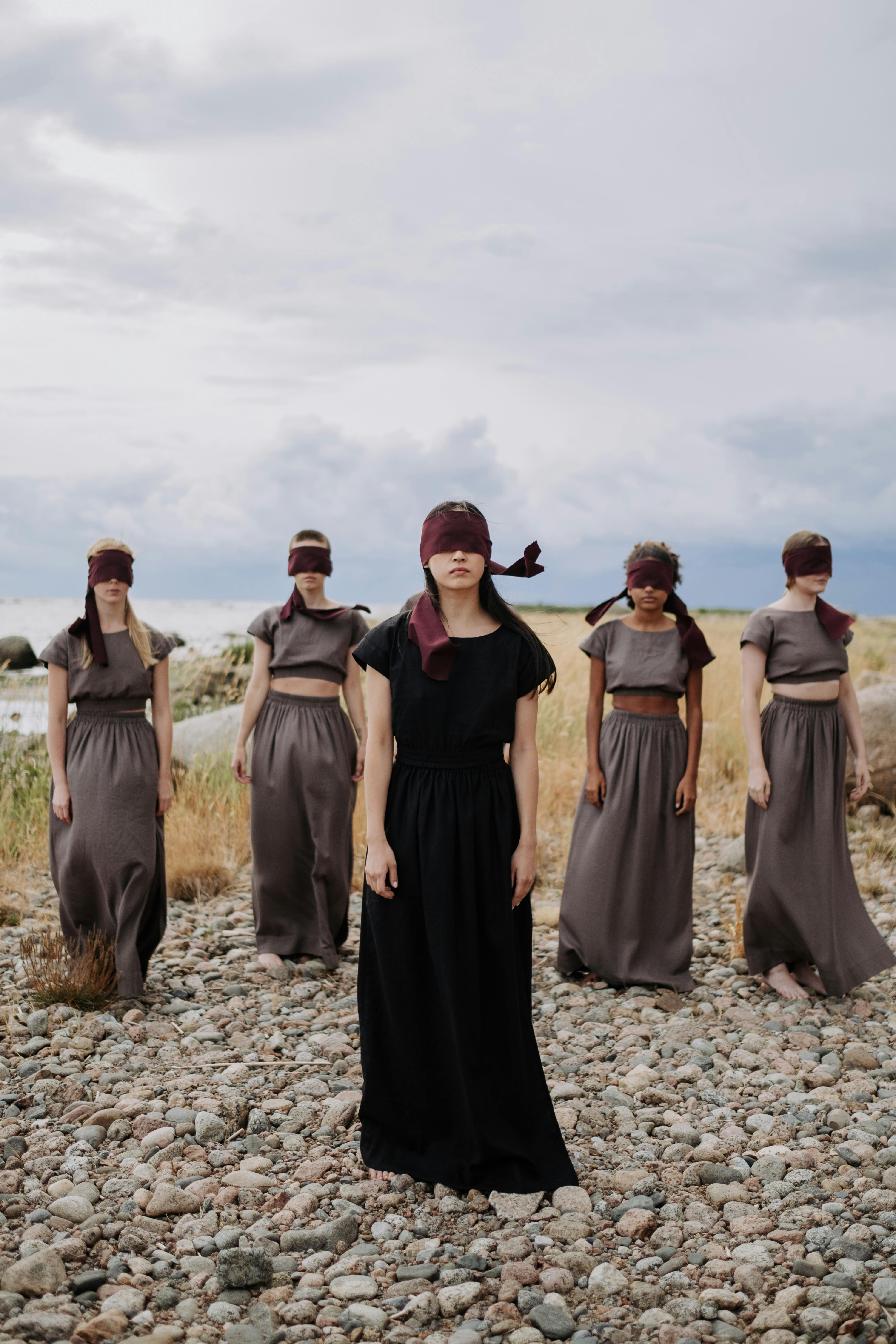 blindfolded women standing on a rocky ground