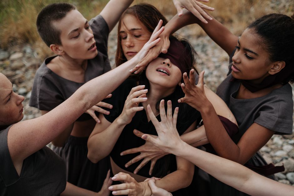 A group of diverse female dancers performing with a blindfold as a creative expression outdoors.