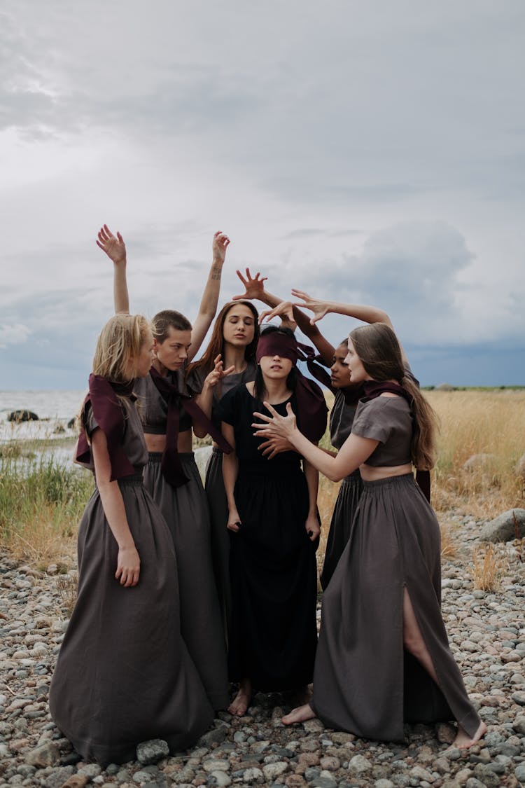 A Blindfolded Woman Surrounded By A Women In Gray Crop Top Dresses