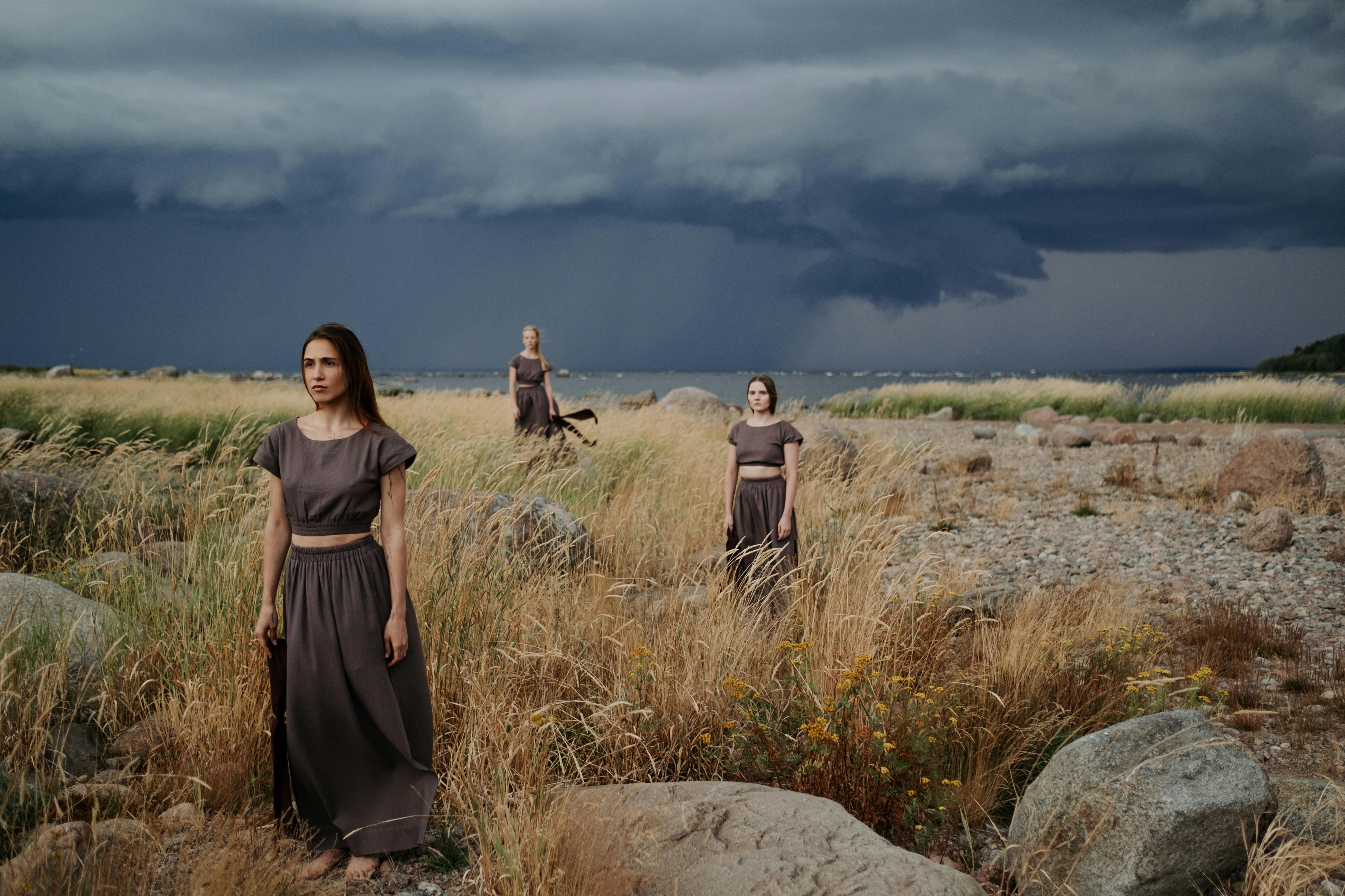 women in long dress standing on a grass field while looking afar