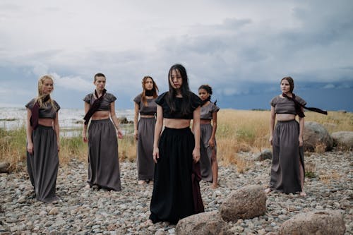 Women in Crop Top and Long Skirts Standing Near a Body of Water