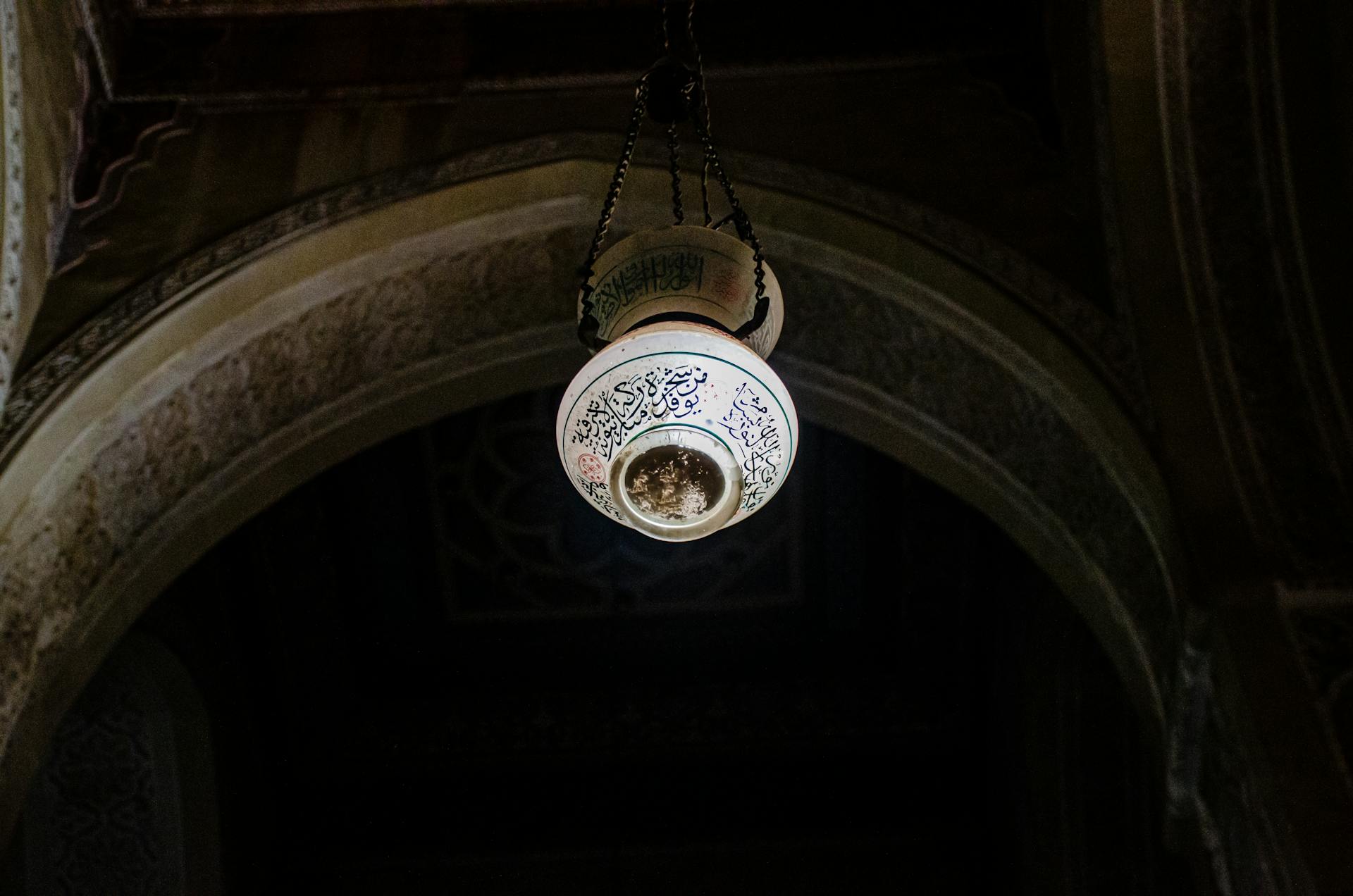 Ornate hanging lamp with Arabic calligraphy in Cairo mosque. Captures unique Islamic architecture.