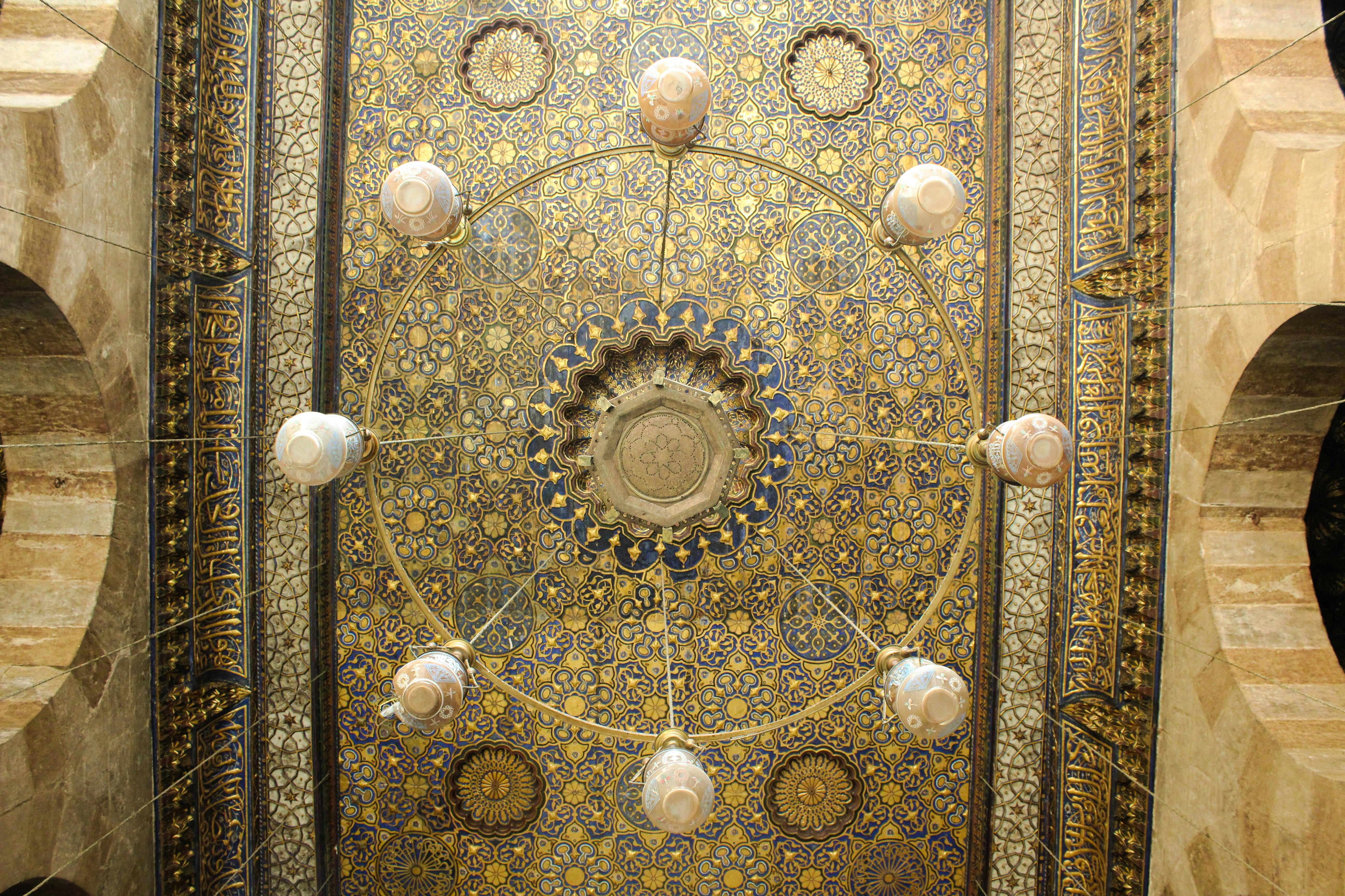 Intricate ornate ceiling with ceramic pendant lamps in Cairo, displaying traditional design elements.