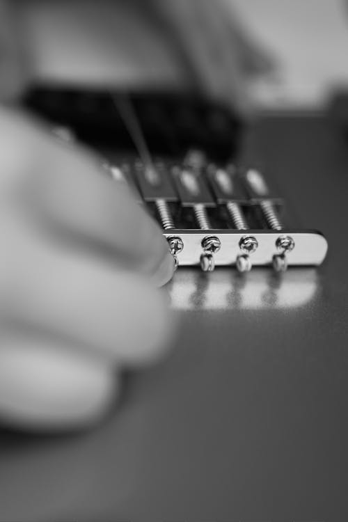 A Person Adjusting a Guitar's Bridge