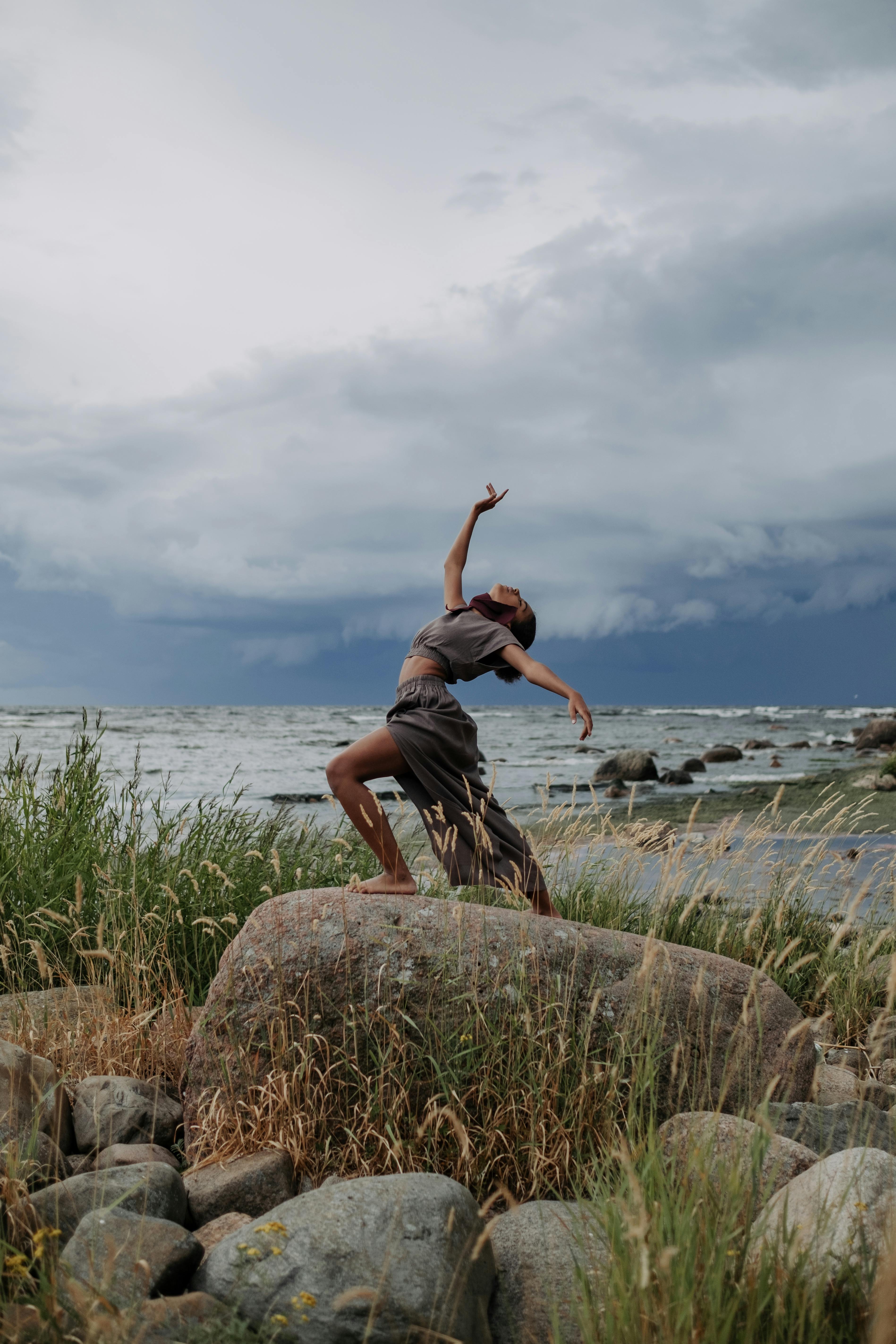 woman dancing on top of a big rock