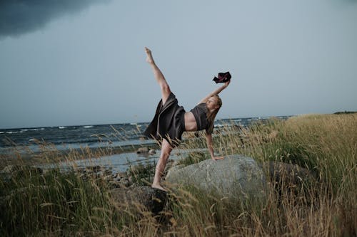 A Woman Standing on the Rock while Raising Her Leg