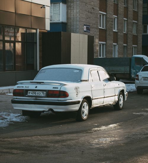 Free White vintage car parked on a snowy city street in winter, showcasing urban life. Stock Photo