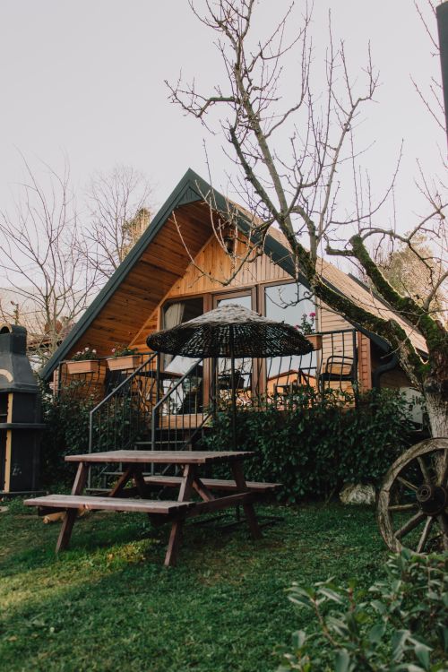 Free A cozy A-frame cabin surrounded by trees, featuring a picnic table and greenery in Sapanca, Turkey. Stock Photo