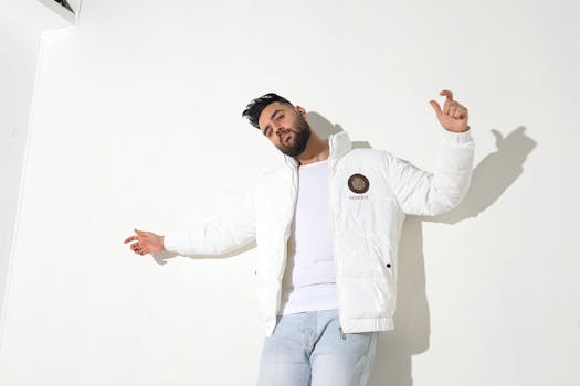 Man wearing a white jacket, posing on a white background, exuding confidence and style.