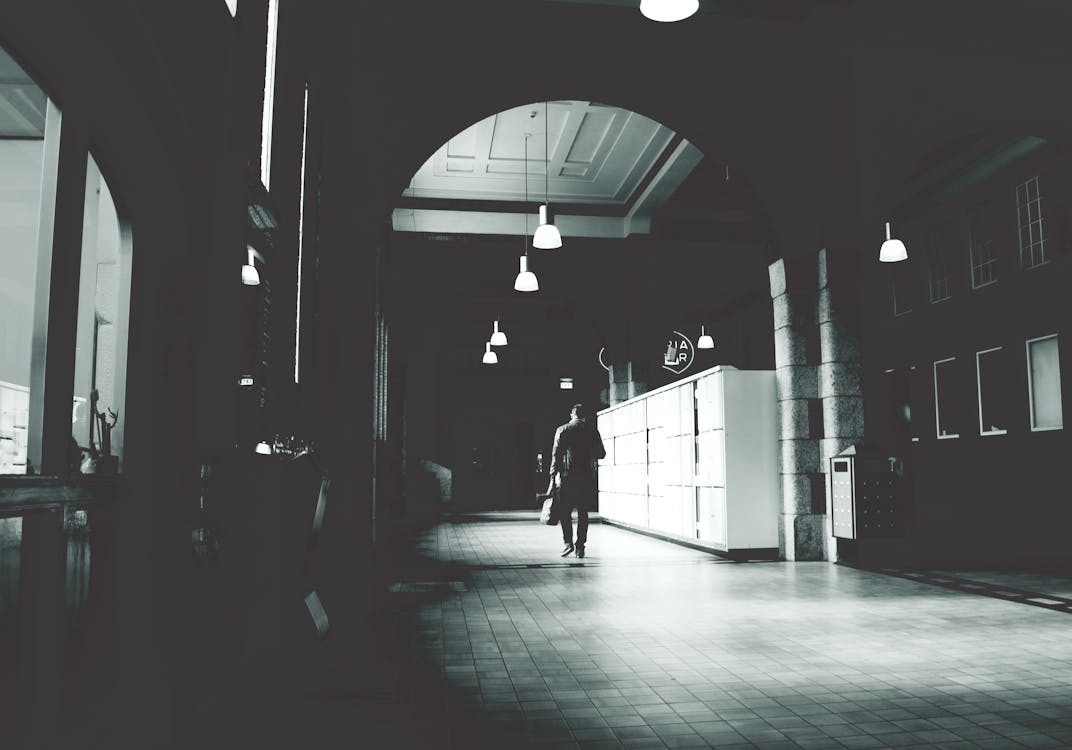 무료 어두운 방에서 흰색 캐비닛 옆에 회색 바닥 타일을 걷는 사람의 실루엣 스톡 사진