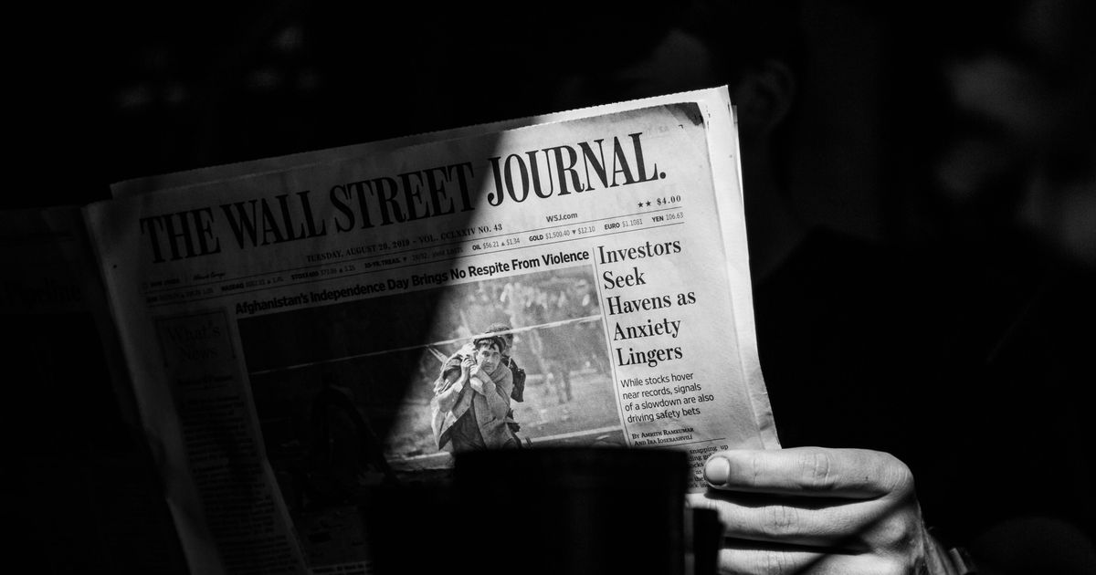 Hand holding a folded Wall Street Journal newspaper, black and white photo