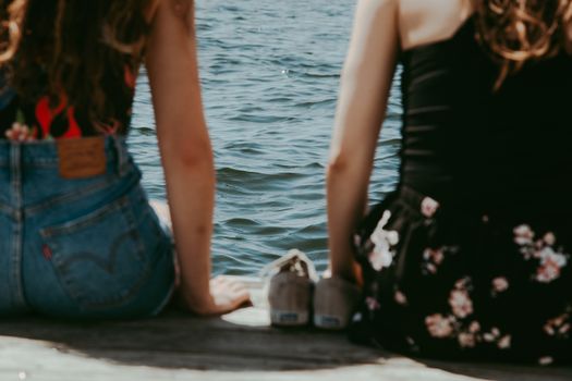 Back View of Two Women Sitting on a Shore in Summer 