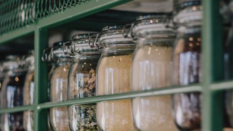 Neatly arranged glass jars with dry ingredients on a kitchen shelf, enhancing storage and organization.