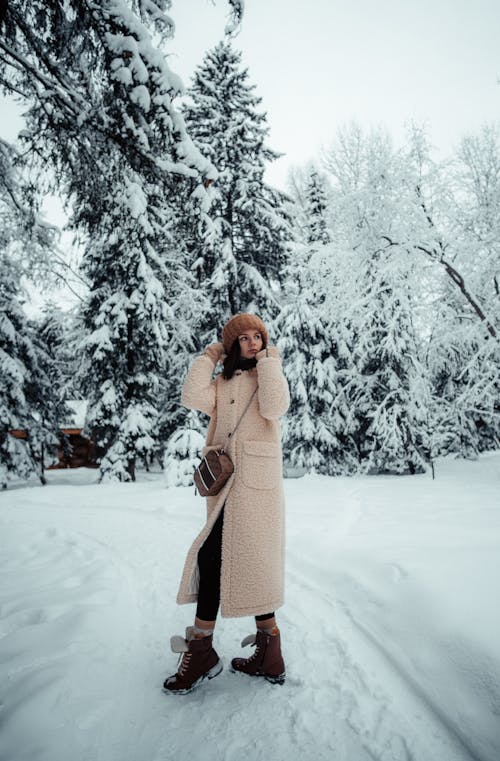 Woman in Winter Coat Standing on Snow-Covered Ground