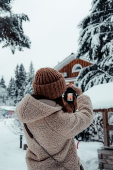 A woman taking photos in a snowy winter setting with a camera.