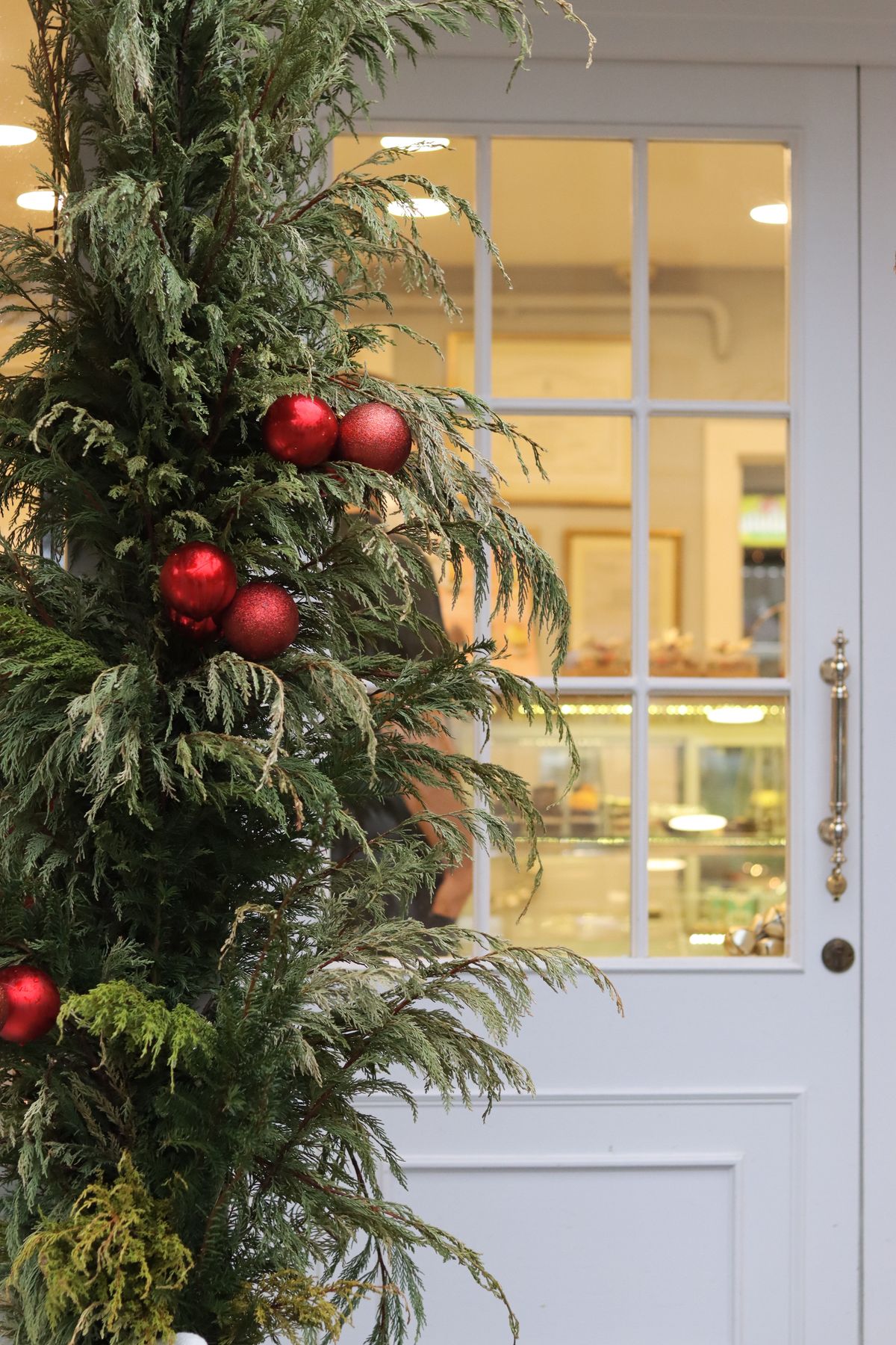 Elegant holiday decorations with red ornaments and greenery at an exterior door