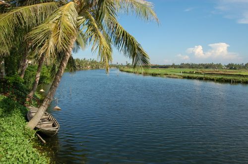 Free Tranquil river scene in Da Nang, Vietnam, featuring a boat and palm trees under a blue sky. Stock Photo