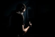 在黑暗、极简的室内环境中，一位成年男子的剪影显得格外戏剧化