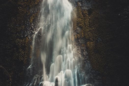 Beautiful waterfall cascading over moss-covered rocks in the serene Tambakdahan, Jawa Barat, Indonesia.
