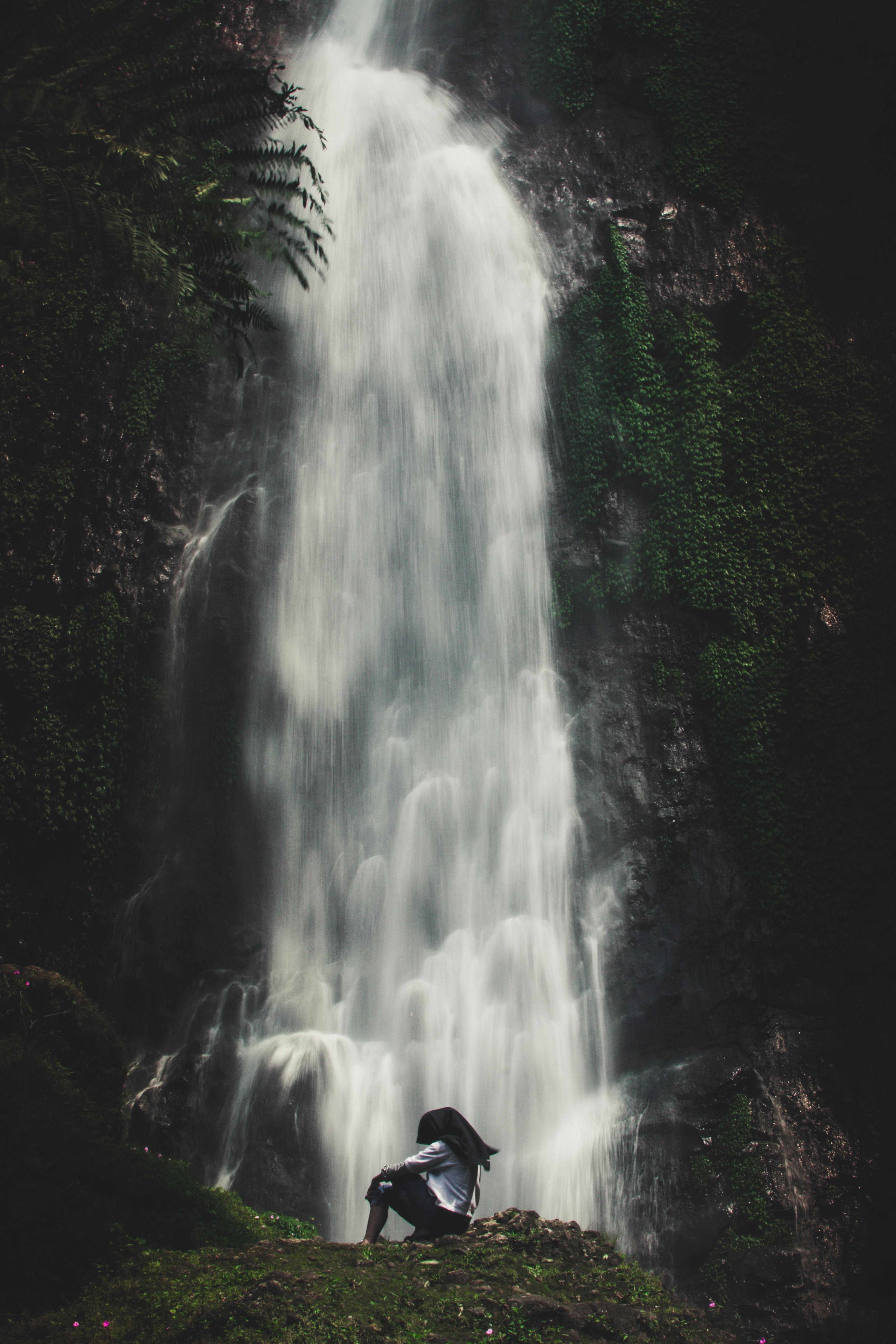 Photo of Man Sitting Near Waterfalls