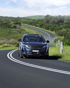 A black car journeys through scenic green landscapes in Wollongong, Australia.