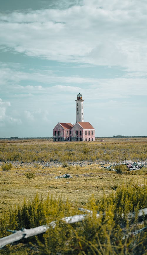 Free A Lighthouse and Concrete House on the Middle of a Grass Field Stock Photo