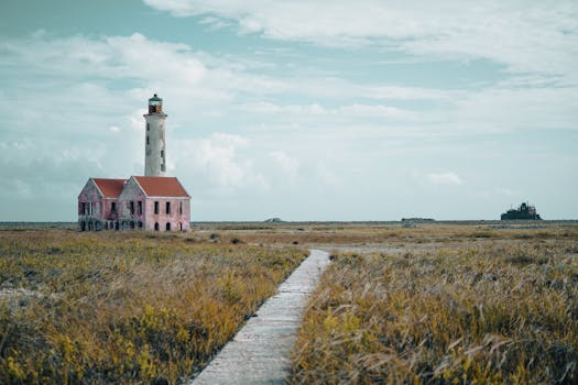 A solitary lighthouse on Curacao's desolate landscape with vibrant sky.