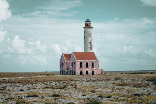 A lone abandoned lighthouse stands in a desolate landscape under a cloudy sky, evoking solitude and history.
