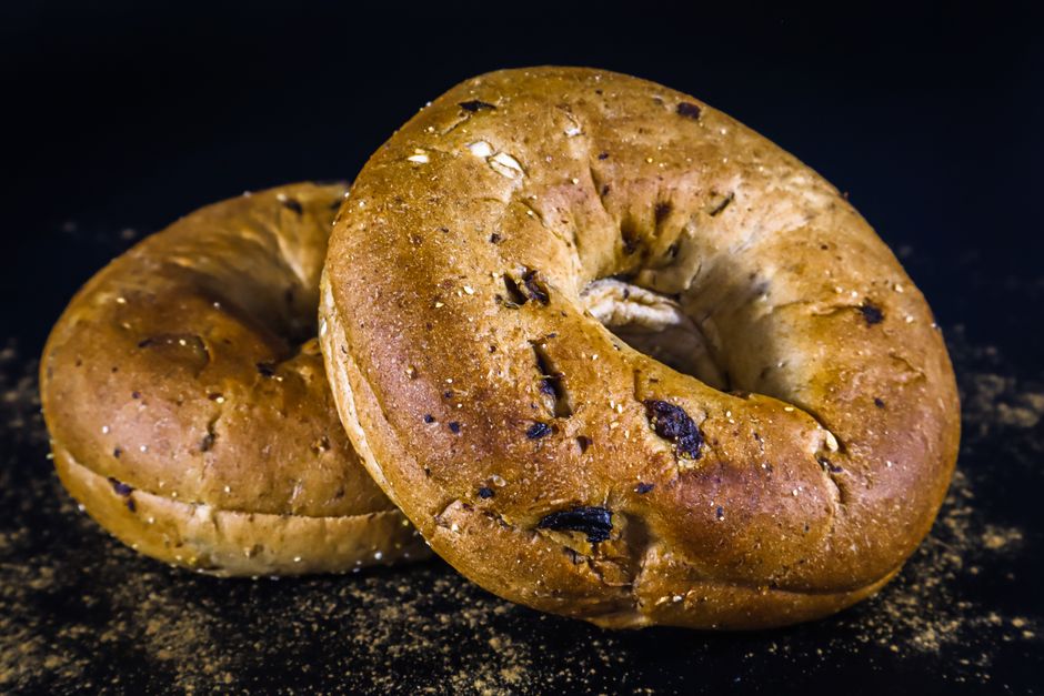 Close-up image of two whole wheat bagels on a dark background, showcasing texture and flavor.