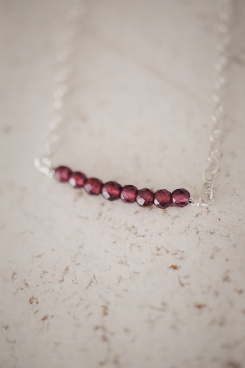 Free Red and Silver Beaded Necklace on a White Surface Stock Photo
