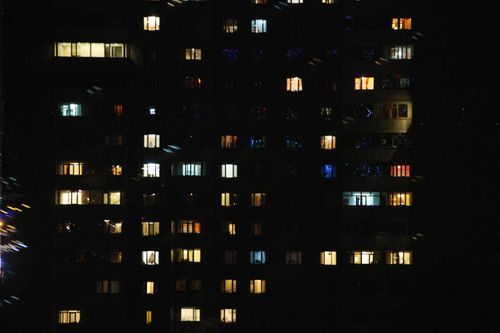 Free A night view of an urban high-rise with various illuminated windows, showcasing city life and architecture. Stock Photo