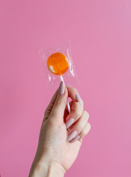 A Person Holding an Orange Lollipop