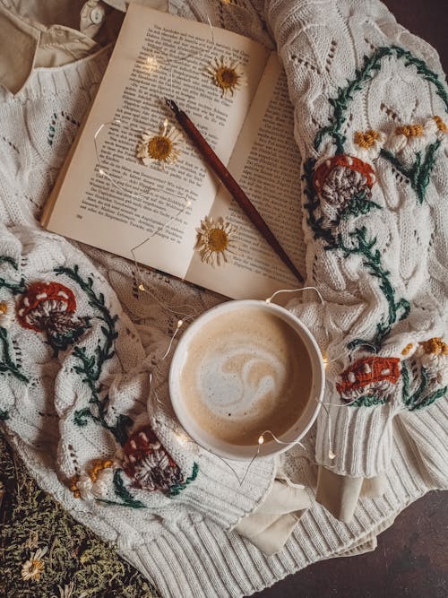 A Knitted Sweater with Open Book and a Cup of Coffee on Top