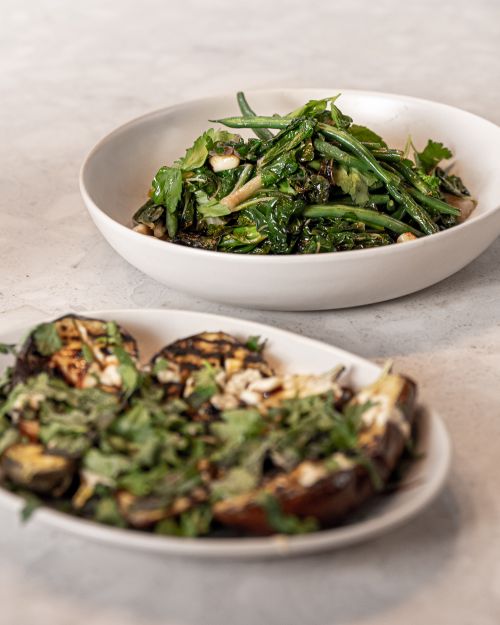 Free Delicious roasted eggplant and greens in a Mediterranean-style meal setting. Stock Photo