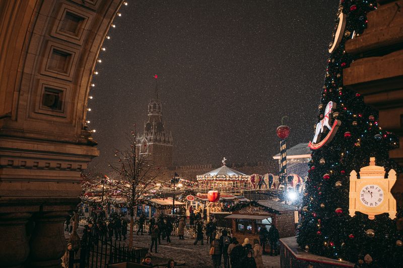 Târg de Crăciun iluminat pe timp de noapte cu standuri festive și decorațiuni strălucitoare