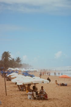 A serene beach setting with umbrellas and people enjoying a sunny day by the sea.